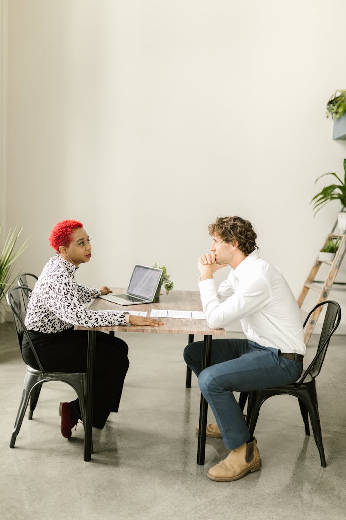 Colleagues engaged in discussion at a table in a modern office environment.